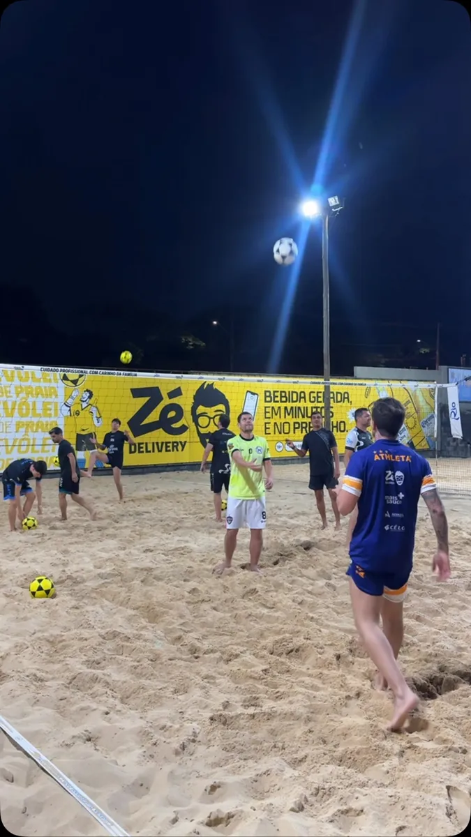 Ian joga futvôlei na areia à noite