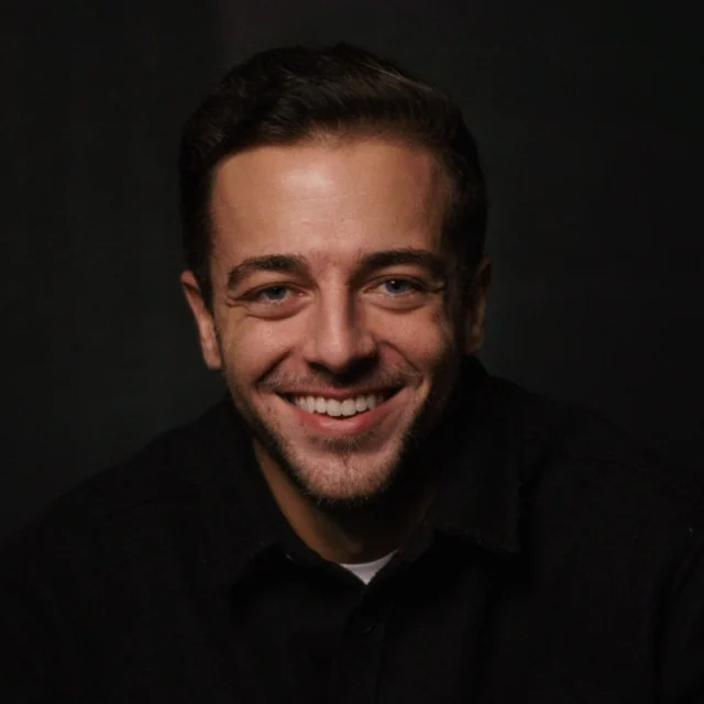 Ian Rezende sorri em retrato com fundo escuro